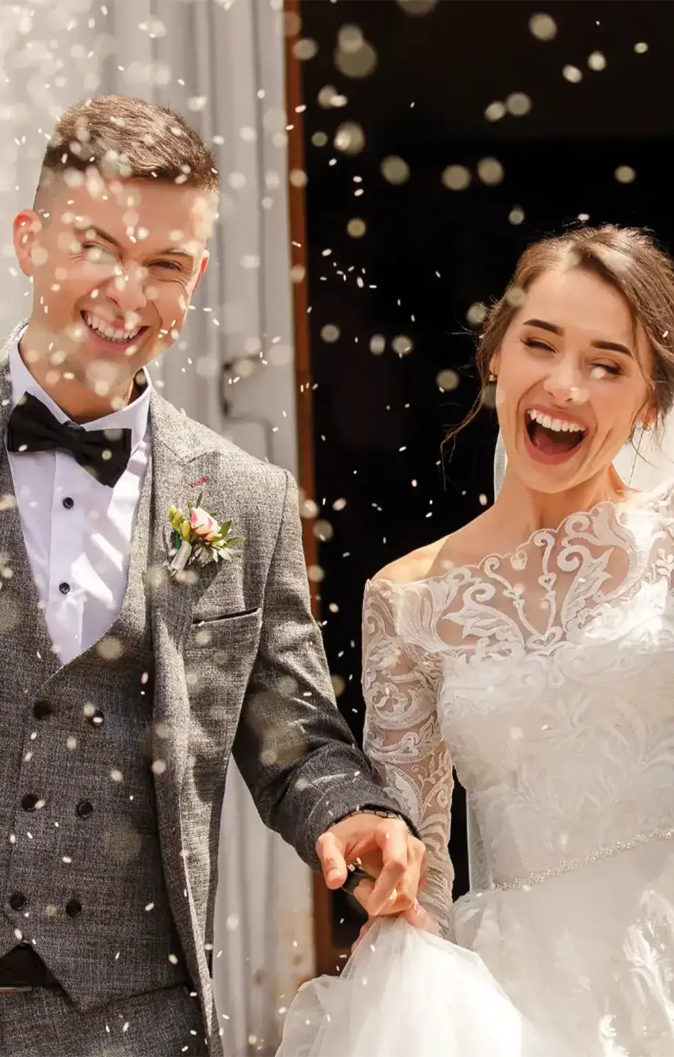 Lachendes Brautpaar, auf dem Bild wird Konfetti geworfen.